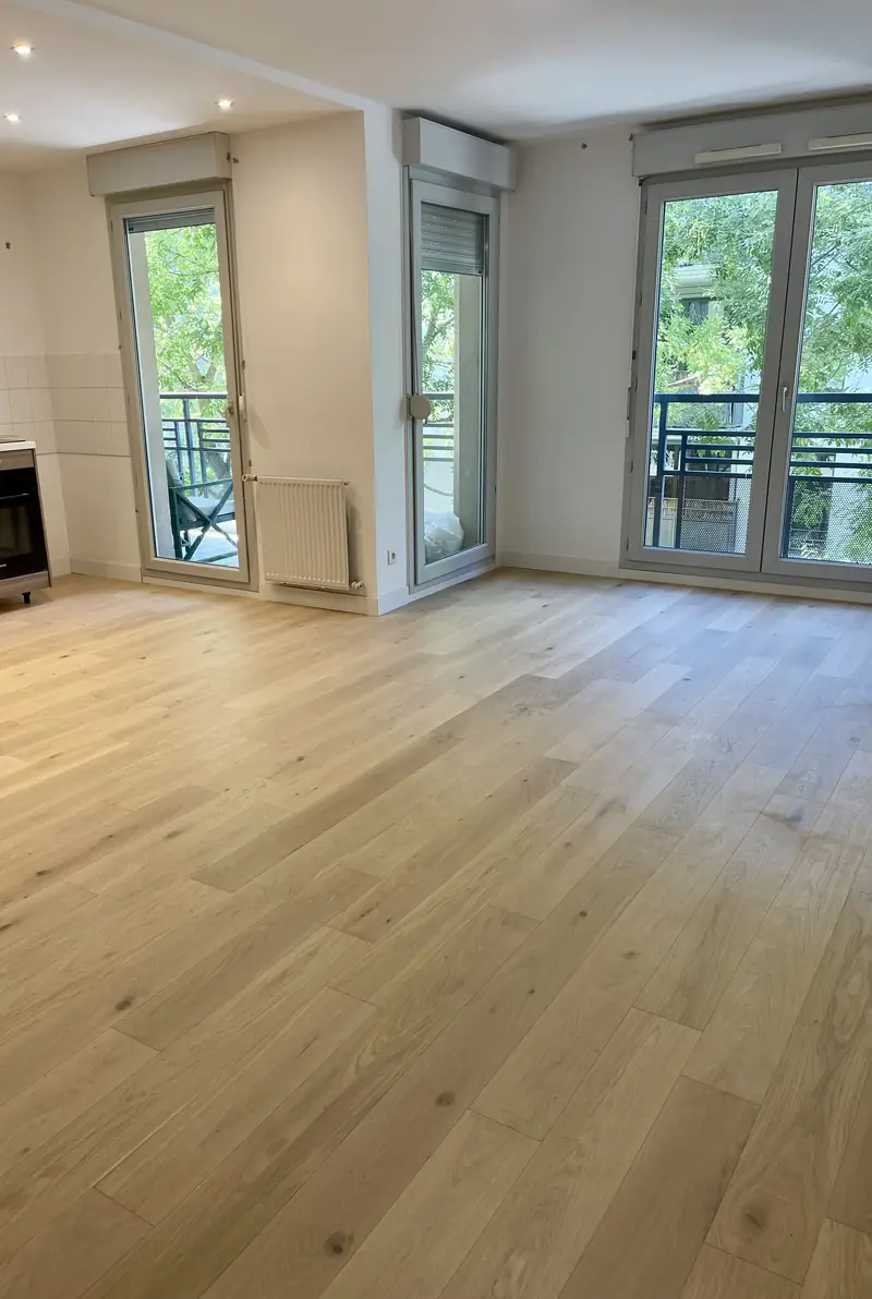Parquet contrecollé en chêne clair posé dans un séjour lumineux avec cuisine ouverte, appartement à Villeurbanne