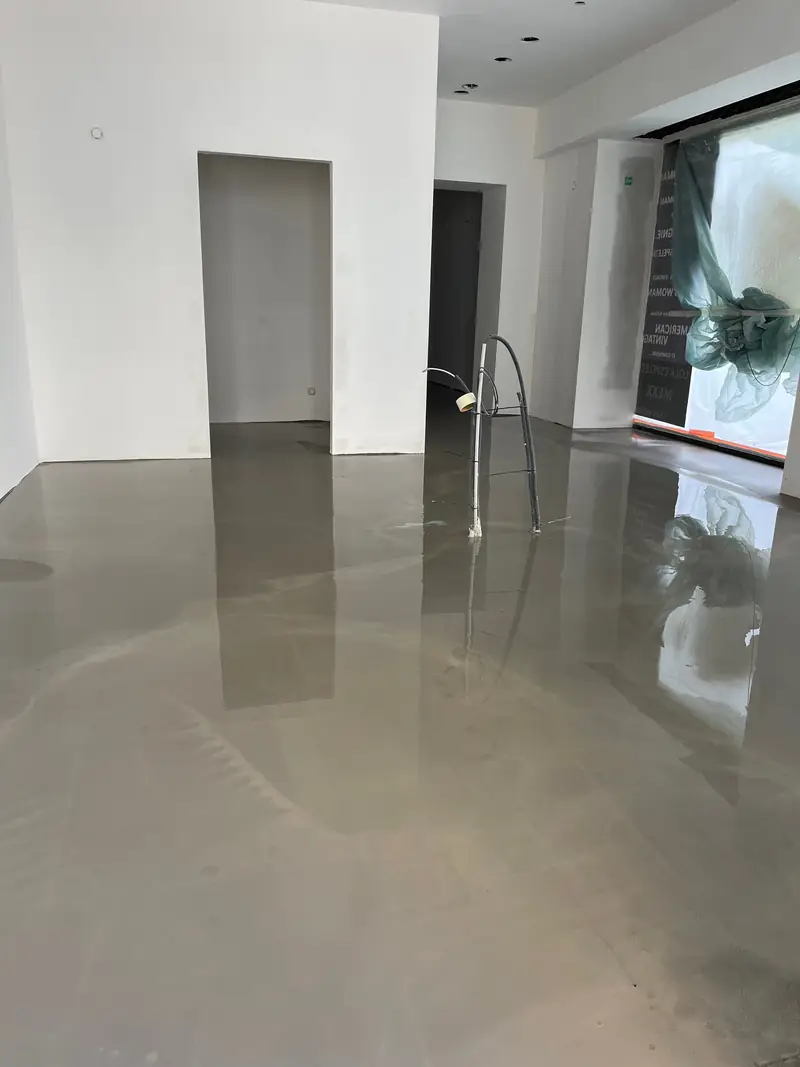 Ragréage autolissant fraîchement coulé dans une boutique d'opticien ATOL à Lyon, avant la pose du revêtement