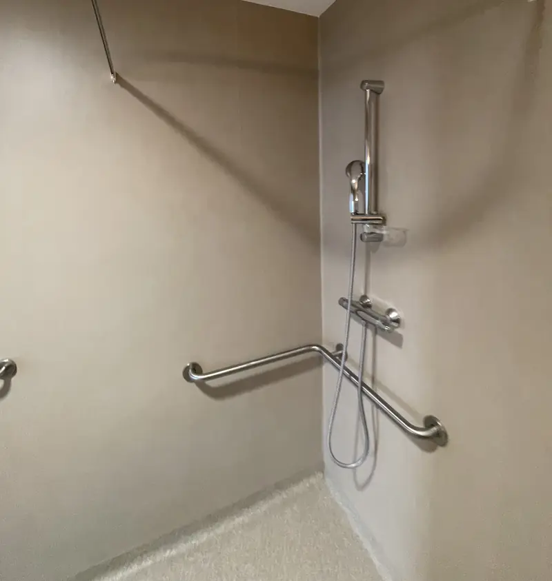 Système de douche PVC soudé à chaud, parois et sol continus avec barres d'appui, dans un EHPAD à Lyon